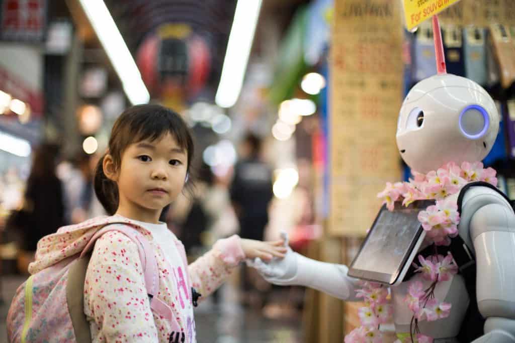 Young Asian girl holding hands with a robot.