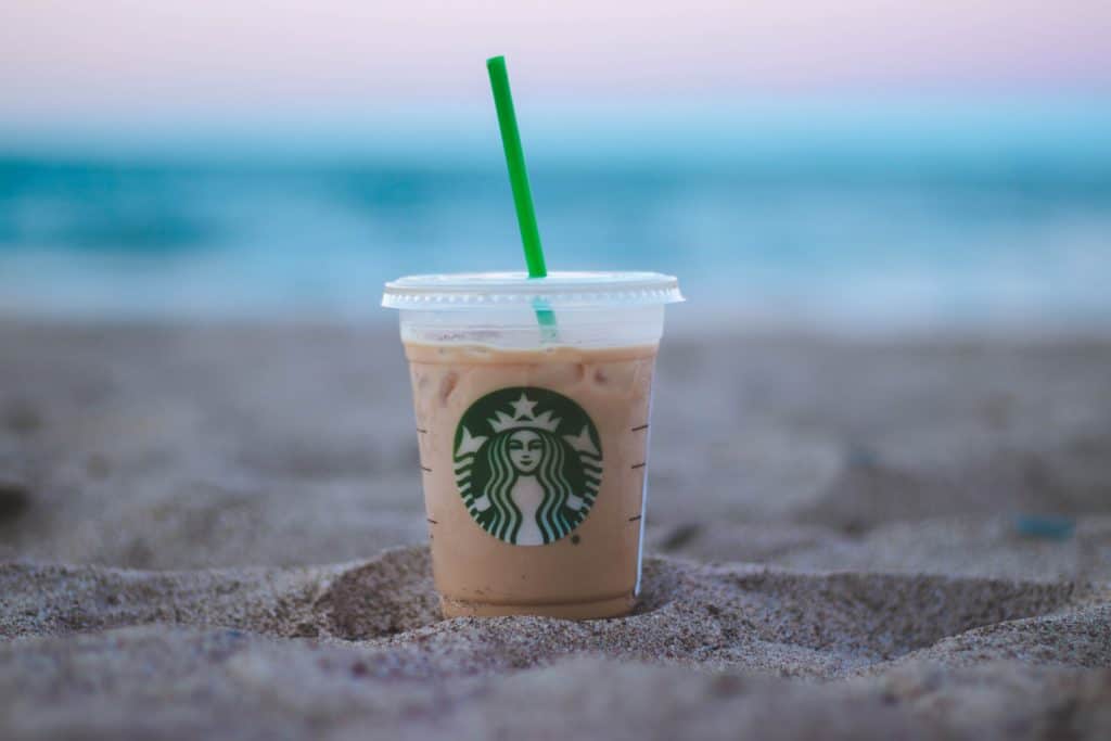 Starbucks plastic coffee cup on beach.