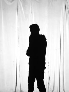 Image depicting the silhouette of a person standing in front of a window